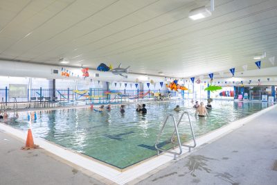 Wide shot of the indoor pool at Logan North Aquatic Centre with numerous people in the pool